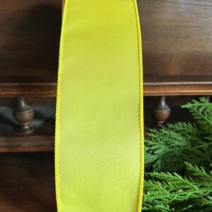 May include: A bright yellow satin ribbon with a wired edge. The ribbon is 2.5 inches wide and has a subtle sheen.