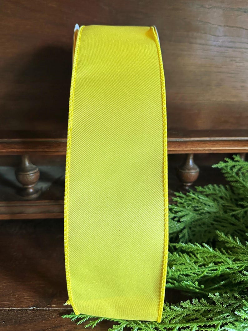 May include: A bright yellow satin ribbon with a wired edge. The ribbon is 2.5 inches wide and has a subtle sheen.