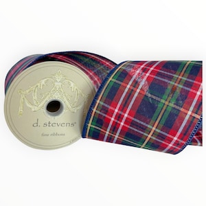 May include: A spool of d. stevens fine ribbons featuring a plaid pattern in red, navy blue, green, and white. The spool has a cream-colored center with ornate gold-toned filigree detailing and the brand name printed in black text on the side.