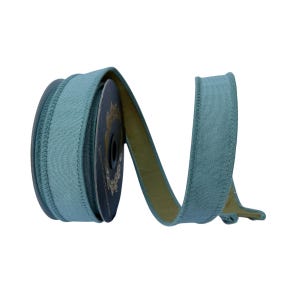 May include: A spool of teal blue ribbon with a textured fabric surface and stitched edges. The ribbon is wound around a dark circular core, with a portion of the ribbon extending outward in a curved, flowing shape, revealing a muted olive green underside.