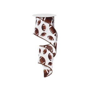 May include: A spool of white ribbon featuring a repeating pattern of brown American footballs with white laces. The ribbon has a dark brown wired edge that runs along the length of the fabric, creating a structured and defined border.
