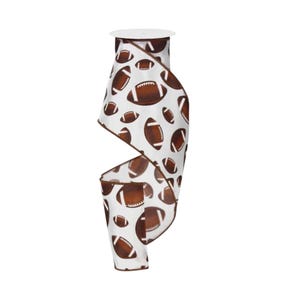 May include: A roll of white ribbon featuring a repeating pattern of brown American footballs with white laces. The ribbon has a brown finished edge and is wound around a central spool, displaying a continuous print of various sized footballs.