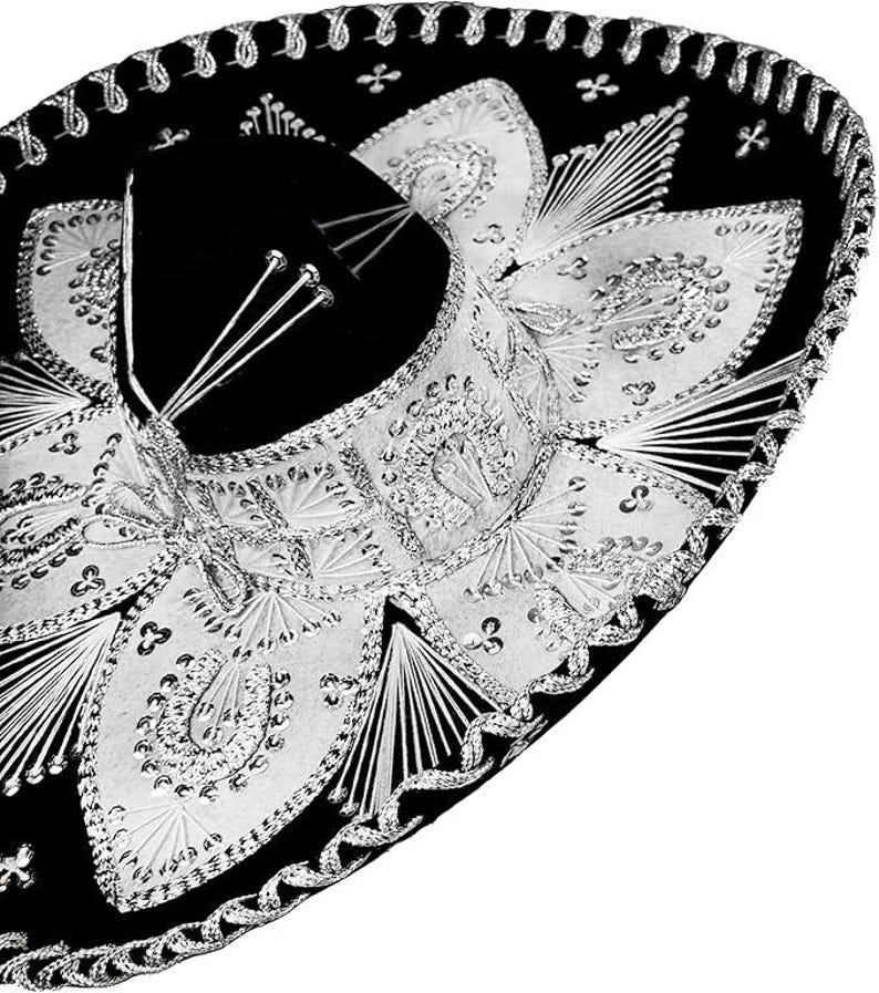 May include: A black sombrero with elaborate silver embroidery and embellishments. The hat features a wide brim and a black velvet crown. The silver detailing includes intricate patterns and decorative trim, creating a festive and elegant appearance.
