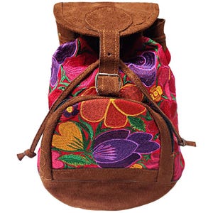 May include: A colorful backpack with a floral embroidered design. The bag features a red background with embroidered flowers in shades of orange, purple, and yellow. It has a brown suede flap and trim, a drawstring closure, and a zippered front pocket.