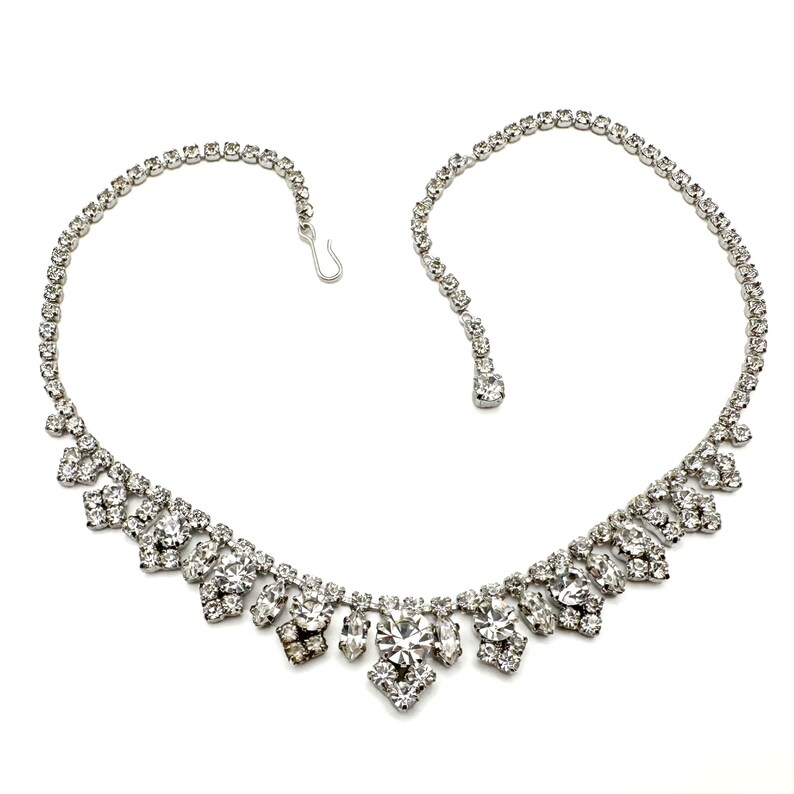 Silver tone retro 1950s clear rhinestone fringe necklace with geometric shape and a hook closure.