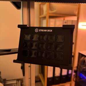 Könnte beinhalten: Ein schwarzes Stream Deck mit 15 Tasten, montiert auf einem Metallständer. Das Stream Deck ist ein Gerät, das für Live-Streaming und Content Creation verwendet wird.
