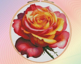 May include: A close-up of a vibrant red and yellow rose cross-stitched on white fabric, framed in a wooden hoop.