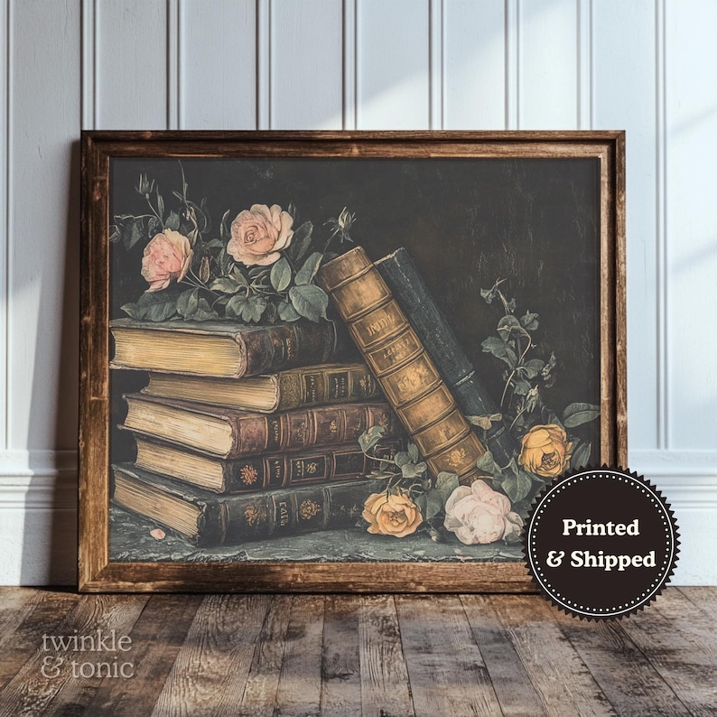Puede incluir: Impresi&oacute;n enmarcada que presenta una naturaleza muerta de libros antiguos y rosas. Los libros est&aacute;n apilados e inclinados, con letras doradas y cubiertas envejecidas. Rosas rosas y amarillas con follaje verde a&ntilde;aden color sobre el fondo oscuro.