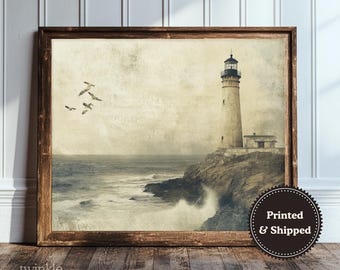 Puede incluir: Una impresión enmarcada de una escena de faro vintage. La obra de arte representa un faro alto y blanco en un acantilado con vistas a un mar tormentoso, con gaviotas en el cielo. La impresión está en un marco de madera y tiene el texto "twinkle & tonic".
