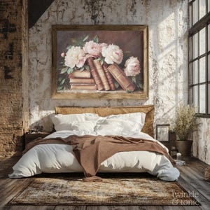 May include: A bedroom scene featuring a bed with white bedding and a brown throw blanket. Above the bed hangs a framed painting of pink peonies and old books. The room has a rustic, vintage aesthetic with a wooden floor and a large window.