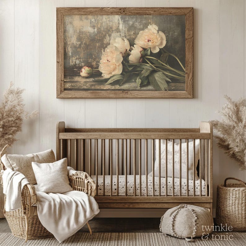 May include: A framed floral print featuring soft pink peonies hangs above a wooden crib. The room is decorated in neutral tones with a wicker chair, throw pillows, and a woven rug, creating a cozy nursery setting.