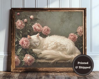 May include: A framed print depicting a white cat resting amidst pink peonies. The artwork has a vintage style with a soft colour palette and a wooden frame. The print is labelled with the text "twinkle & tonic".