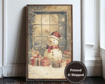 May include: A framed winter scene print featuring a snowman wearing a red hat and scarf, standing in front of a window. The snowman is surrounded by wrapped gifts. The print has a vintage, rustic aesthetic, with the text "Printed & Shipped" on the bottom right.