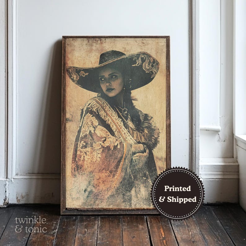 May include: A framed print of a woman wearing a large black hat and a shawl with gold embroidery. The artwork has a vintage, sepia-toned aesthetic. The print is displayed against a neutral background.