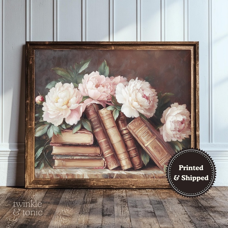May include: A framed print featuring a still life of books and flowers. The artwork showcases a bouquet of pink and white peonies atop a stack of vintage books. The frame is a warm brown color, and the overall aesthetic is classic and elegant.