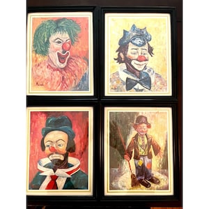 May include: Four framed paintings of clowns. Each painting features a different clown with unique makeup and costumes. The clowns have red noses and painted smiles. The frames are black with gold trim, and the backgrounds are various colors.