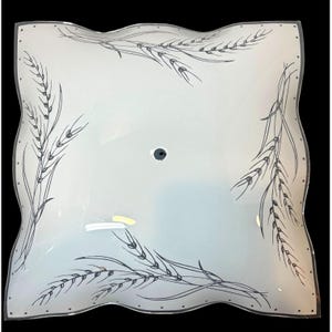 May include: Square, white glass ceiling light fixture with a wavy edge. The fixture has a black and gray wheat stalk design in each corner. A small, dark gray hole is in the center.