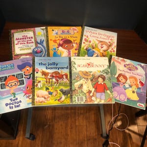 May include: A collection of children's books with colorful covers. Titles include "The Monster at the End of This Book," "As Big as a Whale," and "The Jolly Barnyard." The books feature illustrations of cartoon characters and animals.