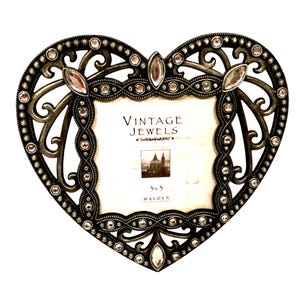 May include: Heart-shaped photo frame with an ornate, antique silver finish. The frame is embellished with clear and pink rhinestones and features the text "VINTAGE JEWELS" and "3x3". A decorative piece for displaying photos.