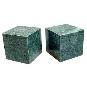May include: Two square, marble bookends. The bookends are a dark green color with lighter green veining throughout. The bookends are cube-shaped and sit on a white background.