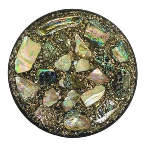 May include: A round, decorative object with a black border. The center is filled with small, granular material and iridescent abalone shell pieces in shades of green, blue, pink, and white. The abalone pieces vary in size and shape.