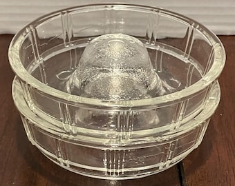 May include: A clear glass citrus juicer with a ridged reamer and a matching bowl. The juicer is made of clear glass and has a classic design. The bowl has a grid pattern around the sides.