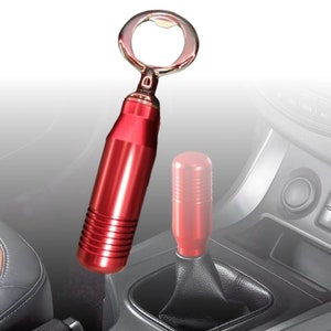 Könnte beinhalten: Ein roter Flaschenöffner mit einem silbernen Flaschenöffner. Der Flaschenöffner hat einen zylindrischen Körper mit geriffeltem Griff. Ein roter Schalthebelknauf ist ebenfalls im Bild.