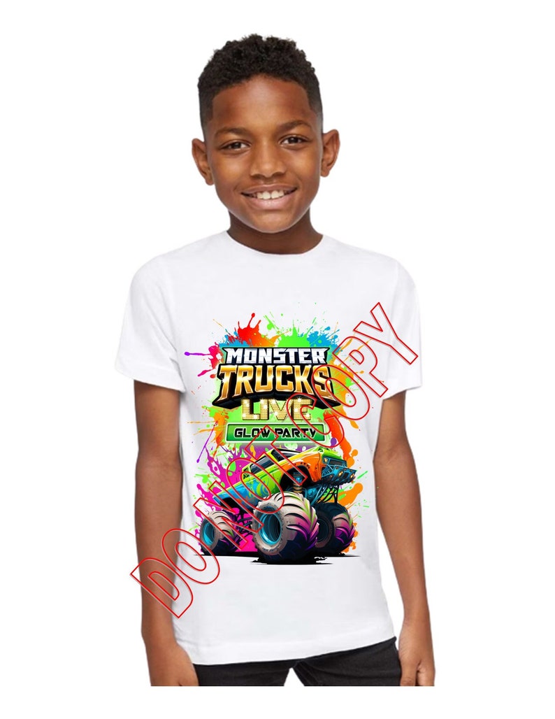Może przedstawiać: Biała koszulka z kolorową grafiką przedstawiającą monster trucka. Grafika zawiera tekst "Monster Trucks Live Glow Party".
