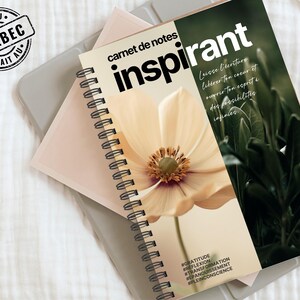 Könnte beinhalten: Ein spiralgebundenes Notizbuch mit dem Wort "inspirant" in großen schwarzen Buchstaben. Das Cover zeigt eine cremefarbene Blume und den Text "carnet de notes". Das Notizbuch liegt auf einer hellgrauen Oberfläche mit einem Stempel "FAIT AU QUÉBEC".