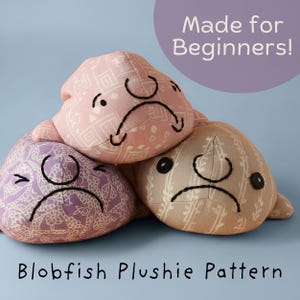 Op de afbeelding: Drie gevulde blobfish knuffels van stof met patronen in roze, paars en beige. Elke knuffel heeft geborduurde gelaatstrekken, waaronder ogen en een naar beneden gerichte mond. De tekst op de afbeelding luidt Made for Beginners en Blobfish Plushie Pattern.