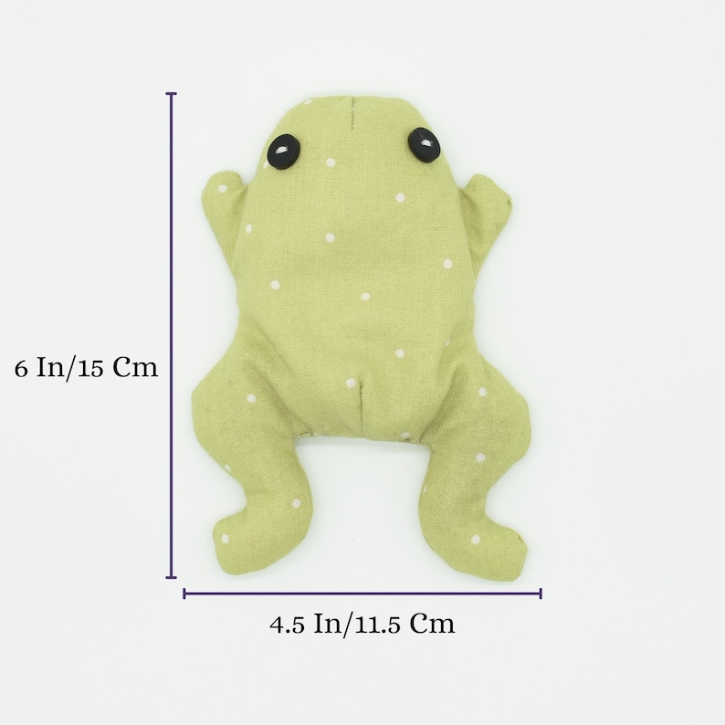 May include: A handmade green frog plush toy with white polka dots. The frog has black button eyes and outstretched limbs. It measures 6 inches (15 cm) in length and 4.5 inches (11.5 cm) wide.