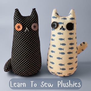 Può includere: Due peluche a forma di gatto fatti a mano. Uno è nero con pois bianchi, l'altro è color crema con motivi di pesci blu. Entrambi hanno occhi a bottone e dettagli cuciti. Il testo "Learn To Sew Plushies" è in basso.