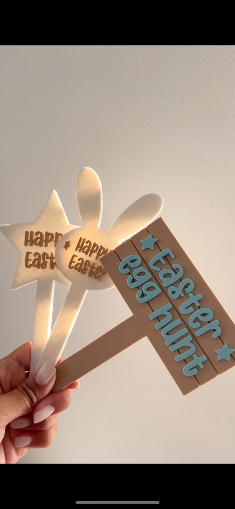 May include: Easter-themed yard stakes. The image shows three decorative stakes: a star, a bunny, and a sign that reads "Easter egg hunt." The stakes are white and brown with blue text. Perfect for Easter.