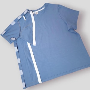 May include: A light blue short-sleeved t-shirt with white trim along the seams. The shirt is folded in half and laid flat.