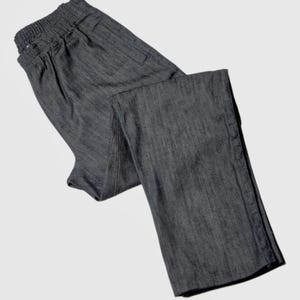 K&ouml;nnte beinhalten: Eine dunkelgraue Hose mit einem Kordelzugbund und einem Rei&szlig;verschluss an der Seitennaht.