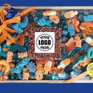May include: A wooden tray filled with assorted colorful candies, including gummy sharks, rings, and ice pops. The tray is decorated with a blue and orange bow and a sticker that says "Sugar Crazy". The center features a square with the text "YOUR LOGO HERE".
