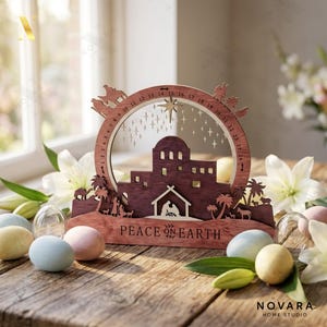 May include: A wooden Christmas advent calendar with a nativity scene design. The calendar features a circular frame with numbers, a star, and the words "Peace on Earth". The wooden structure is brown with a clear background.