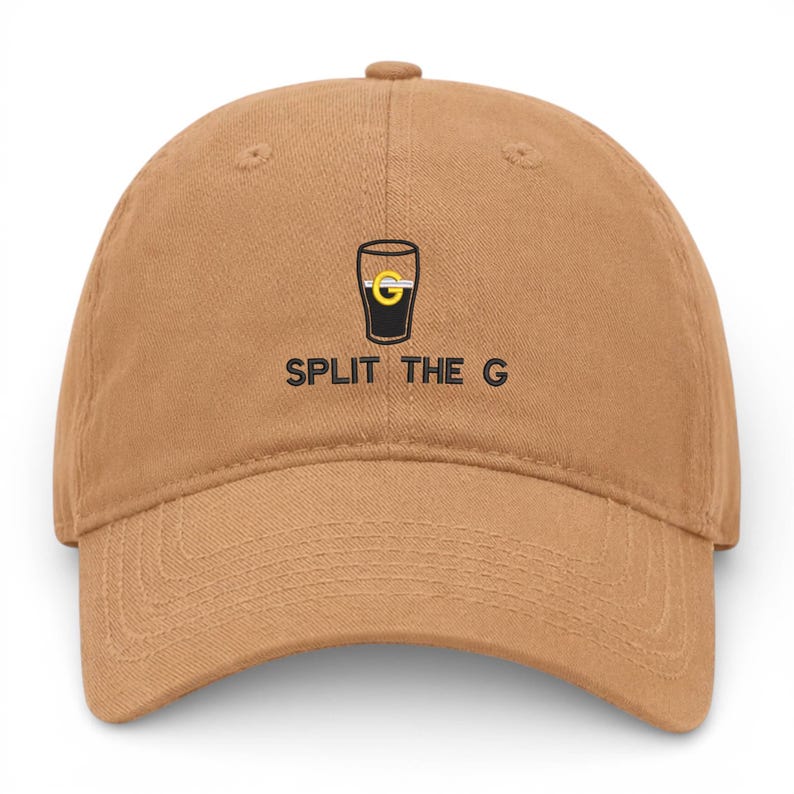 May include: A tan baseball cap with a curved brim. The cap features a black and yellow graphic of a pint glass with the text "SPLIT THE G" in black, centered below the graphic. The cap is made of a soft fabric.