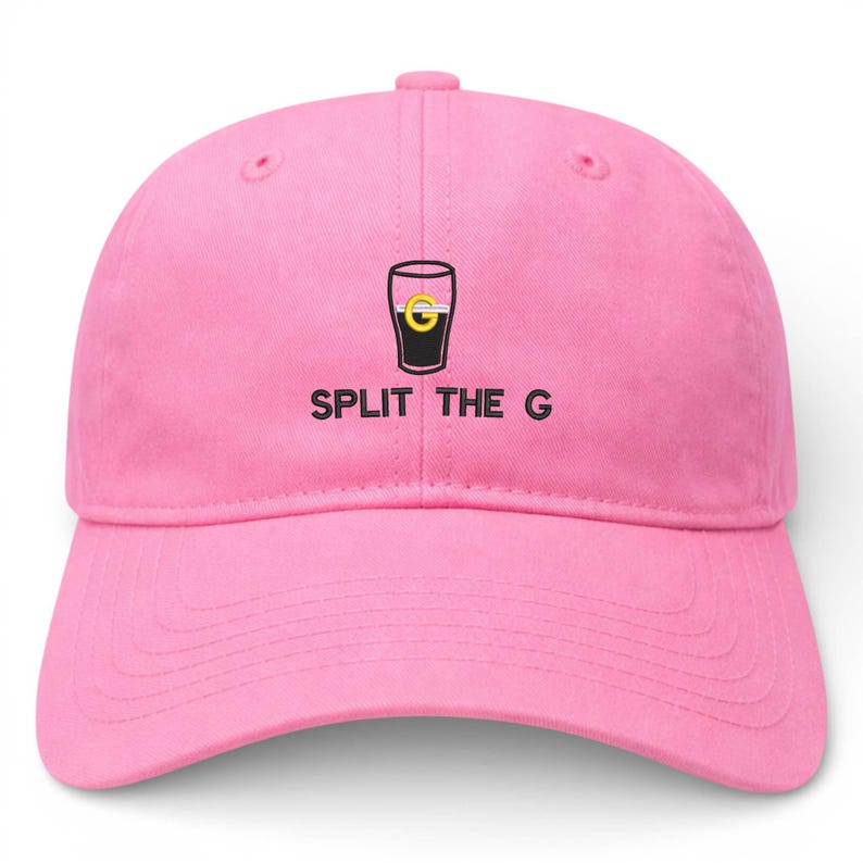 May include: A pink baseball cap with a curved brim. The cap features a graphic of a pint glass with a yellow and black design, and the text "SPLIT THE G" in black letters.