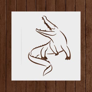 May include: A brown line drawing of an alligator with its mouth open, set against a white background. The alligator is in a dynamic pose, with its body curved and its tail extended. The image is on a wooden background.