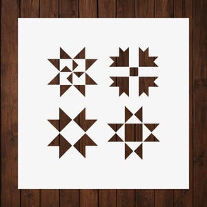 May include: A square stencil featuring four distinct geometric star patterns arranged in a grid. Each design is composed of dark brown triangular and square cutouts, creating sharp, angular shapes against a plain white background surface.