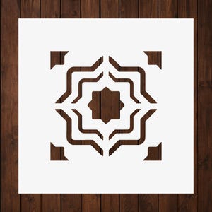 May include: A square white stencil featuring a central eight-pointed star surrounded by concentric, wavy, angular lines that form a symmetrical geometric pattern, with small triangular corner accents completing the design.