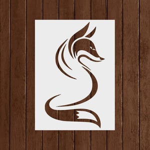 May include: A stencil featuring a stylized fox design. The fox is depicted in a flowing, curved line art style, with a pointed ear and a curled tail. The fox is a dark brown color against a white background.