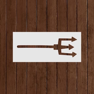 May include: A white stencil of a trident with three arrow-shaped tines and a long handle. The stencil is set against a dark brown, wood-grain background.