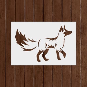 May include: A stencil featuring a stylized fox silhouette in brown against a white background. The fox is depicted in profile, walking with its tail held high. The image is set against a dark brown wood grain backdrop.