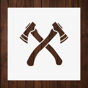 May include: A stencil design featuring two crossed axes in a dark brown wood grain pattern. The axes are positioned symmetrically against a plain white square background, creating a clear and distinct graphic representation of two overlapping tools.