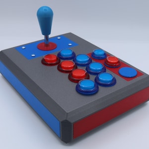May include: A custom-built arcade joystick with a gray body, red and blue accents, and a blue joystick. It features red and blue buttons arranged in a classic layout, perfect for retro gaming enthusiasts.