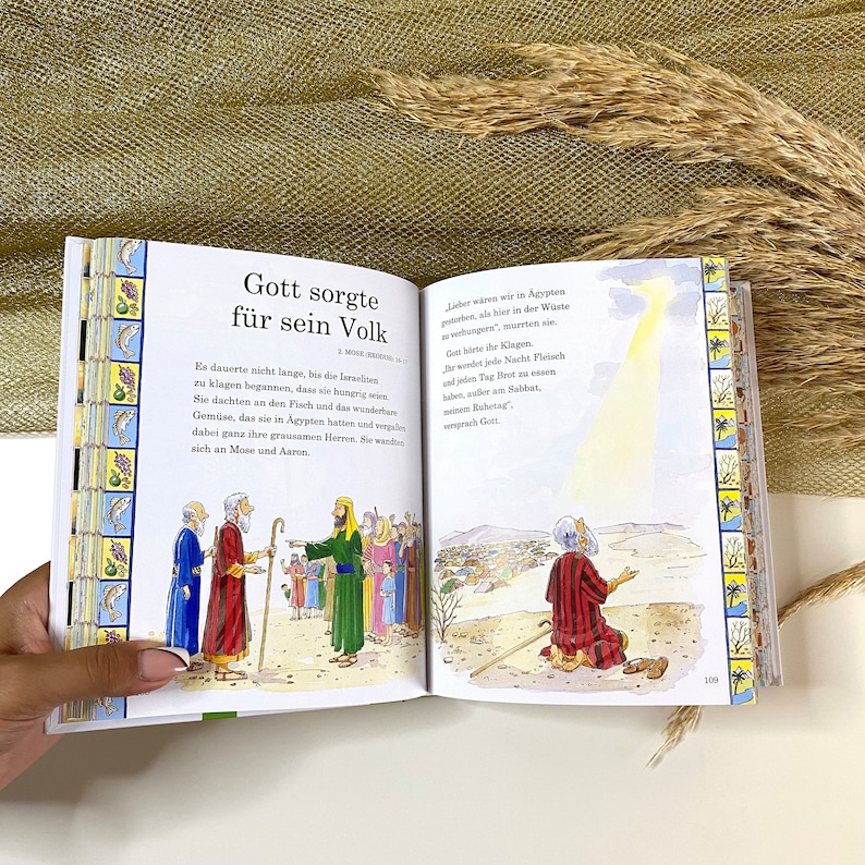May include: An open book with colorful illustrations depicting a biblical story. The text on the page reads "Gott sorgte fur sein Volk" which translates to "God cared for his people".
