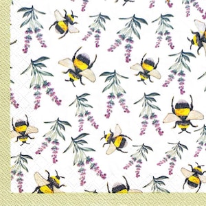 May include: White paper napkin featuring a repeating pattern of yellow and black bees and sprigs of purple lavender. The bees are in different poses, and the lavender has green leaves. The napkin has a light green border.