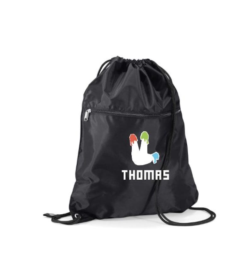 Peut inclure: Sac &agrave; cordon noir avec le nom "THOMAS" en lettres blanches. Le sac pr&eacute;sente un motif blanc avec des gouttes de peinture rouge, verte et bleue. Il comprend une poche zipp&eacute;e et des cordons noirs. Fabriqu&eacute; en mat&eacute;riau durable.